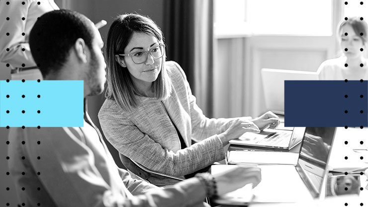 Two colleagues having a discussion in front of their laptops