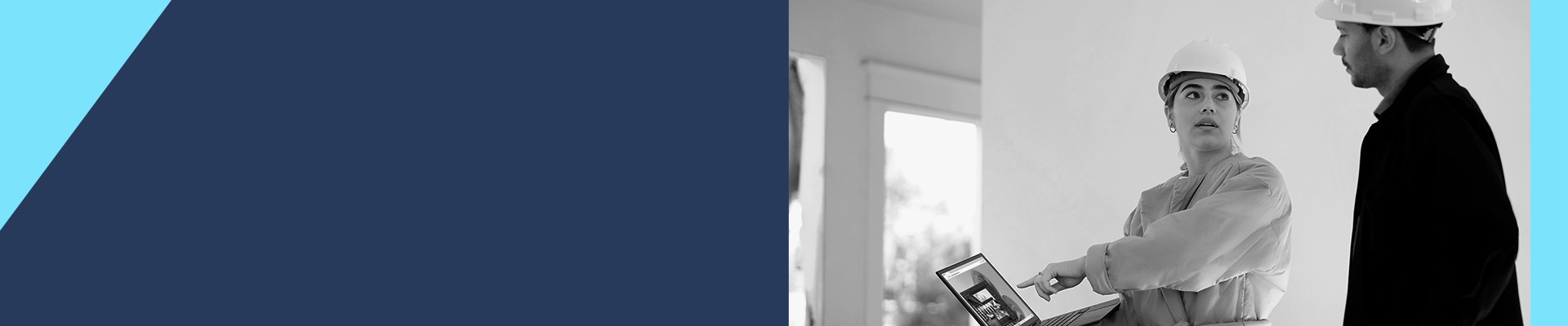 Two people wearing hard hats looking at a tablet