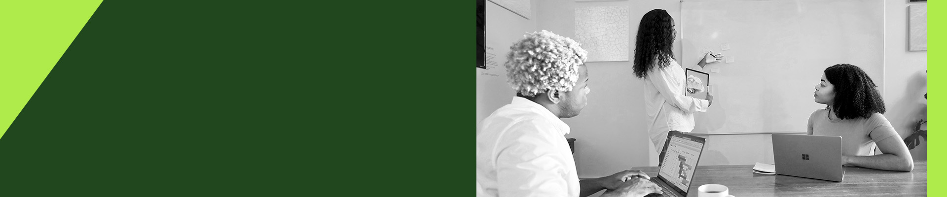 One person presents sticky notes on a whiteboard while another, seated at a laptop, follows along.